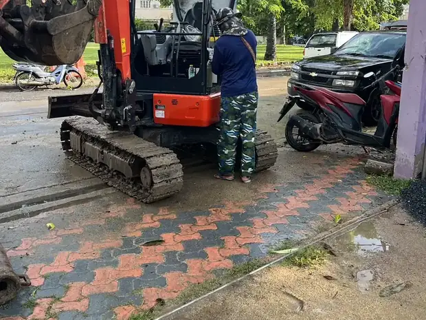 รถขุดขนาดเล็กทำงานในพื้นที่แคบข้างอาคาร