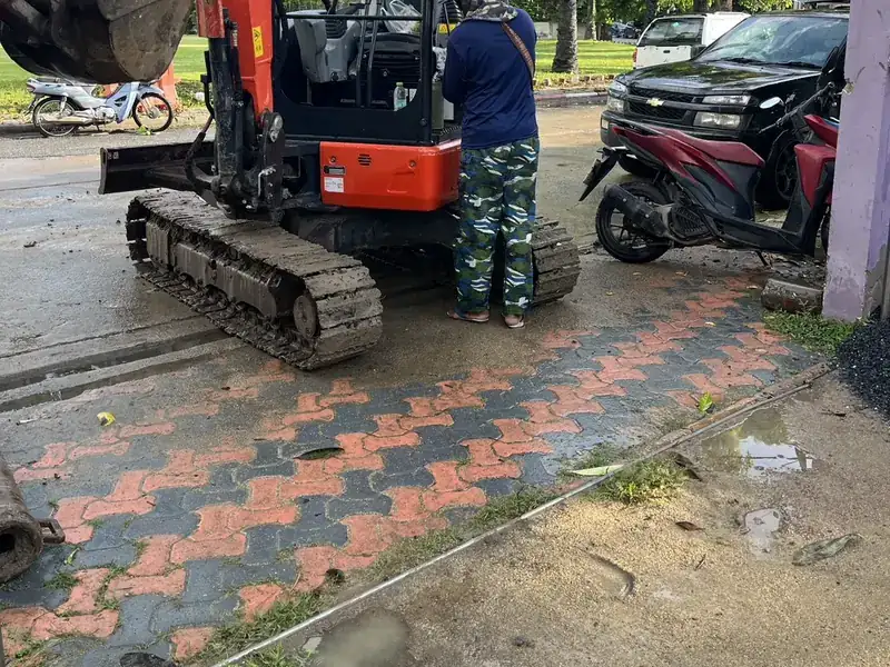 รถขุดทำงานบนพื้นบล็อกปูหน้าอาคารในปากเกร็ด